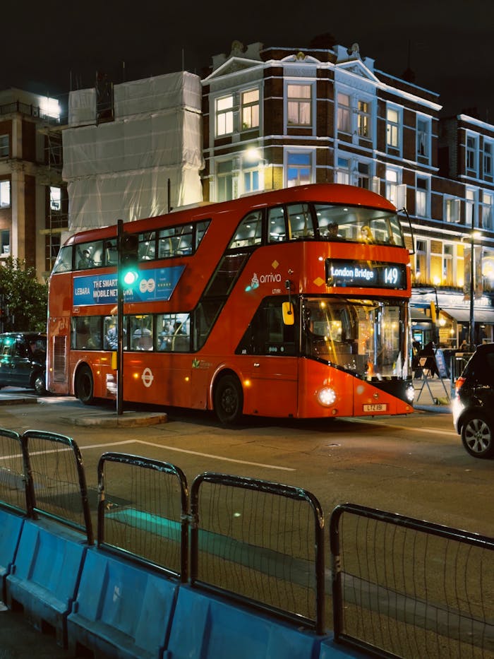 Classic red double-decker bus navigating London's vibrant streets at night.